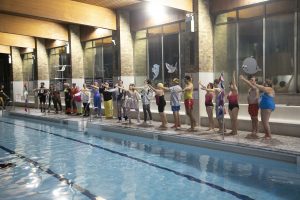 Cast members lining the pool at a community centre